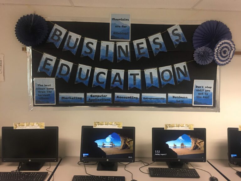 A classroom with three computers and a bulletin board.