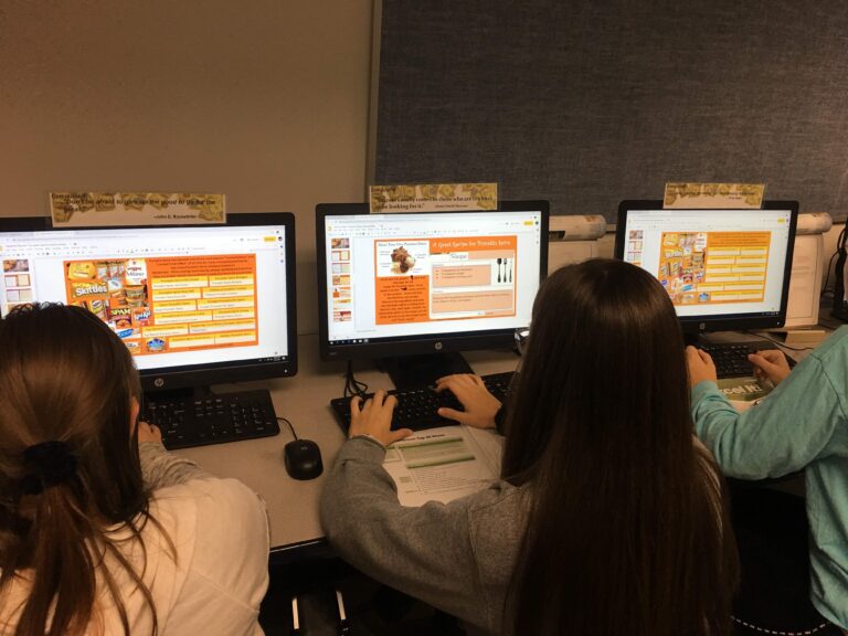 A group of people sitting at computers in front of windows.