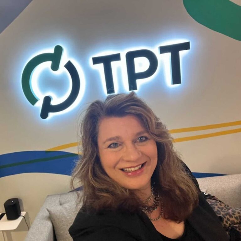 A woman sitting in front of a tpt sign.