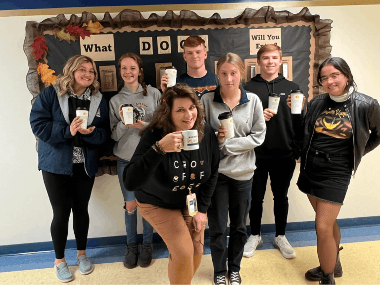 A group of people holding mugs in front of a wall.