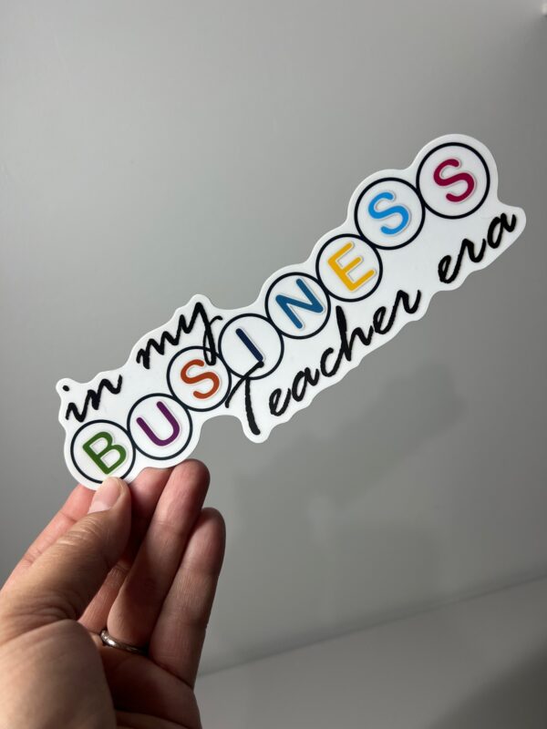 A person holding up a sticker that says in my business teacher era.